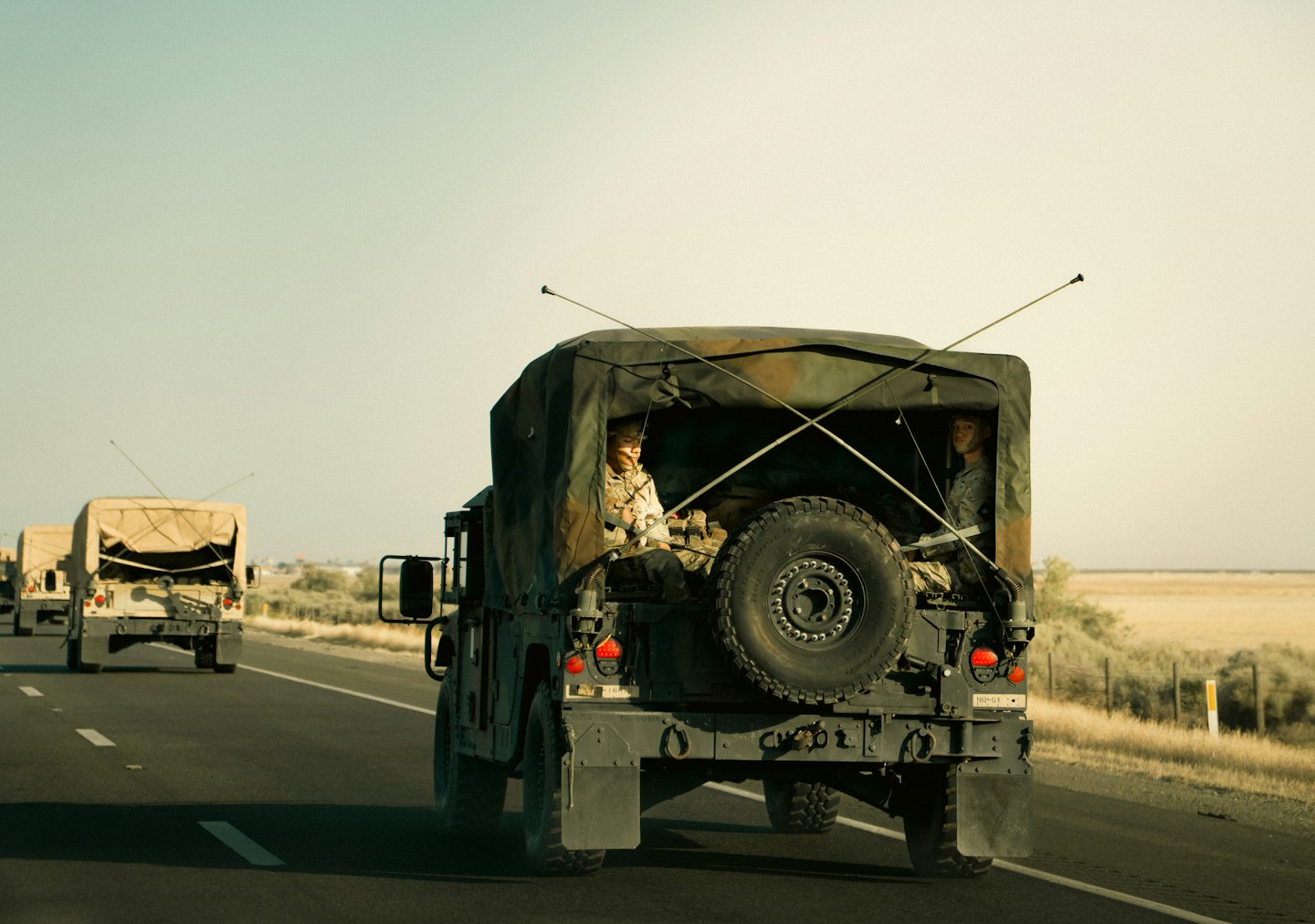 Militärlastwagen fahren auf einer trockenen Straße mit Soldaten im Laderaum.
